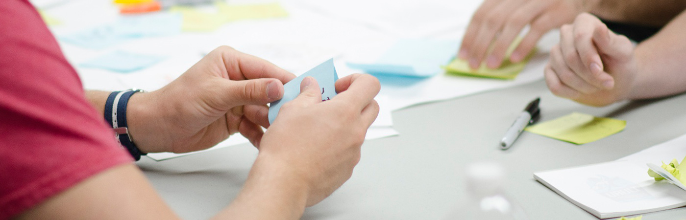 people sat around table with pens, charts and post-it notes